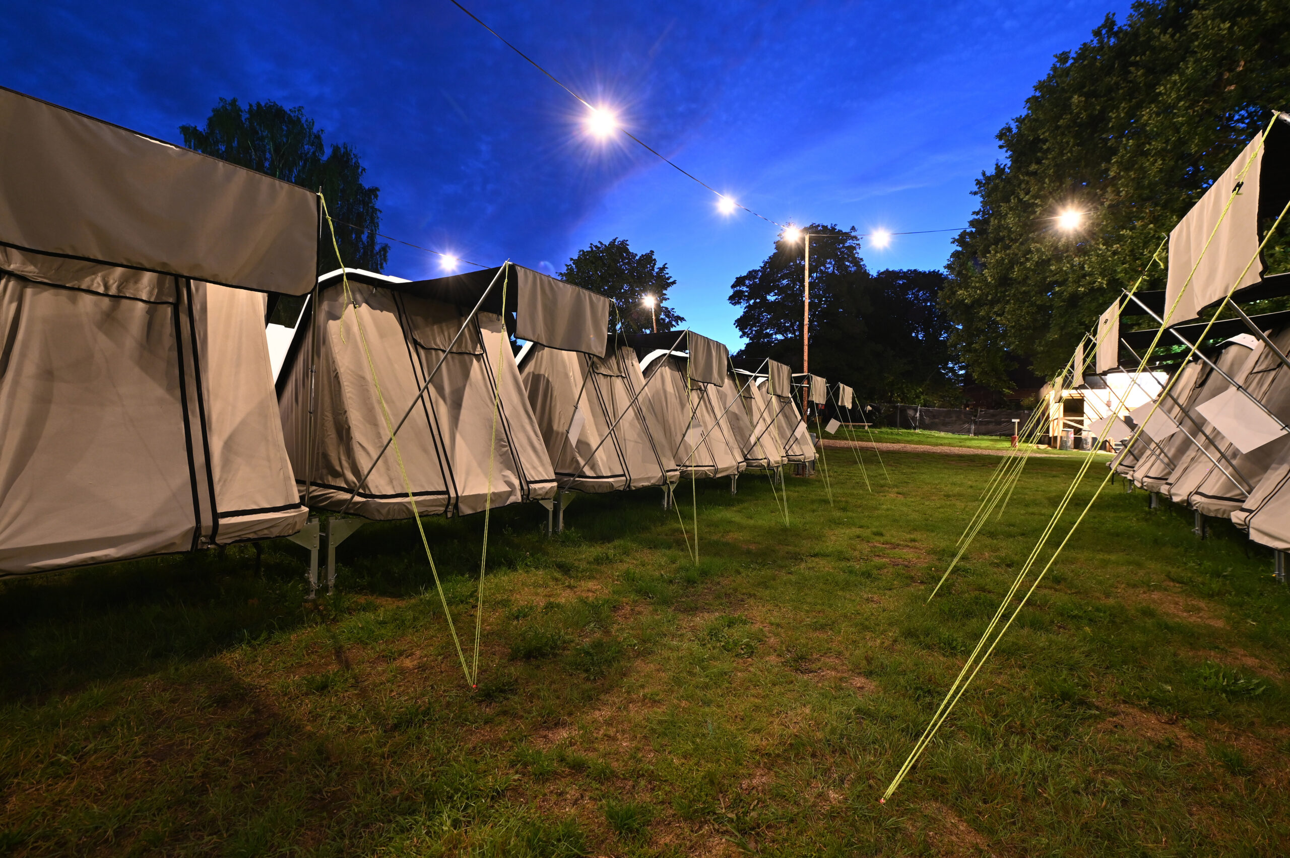 Rækker af opstillede telte på Lux Camp til Skive Festival under en blå aftenhimmel med lyskæder.