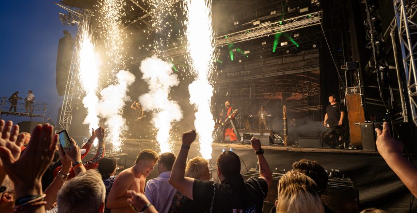 Publikum jubler foran scenen på Skive Festival, mens pyroteknik skyder op under en koncert på Strandtangen.