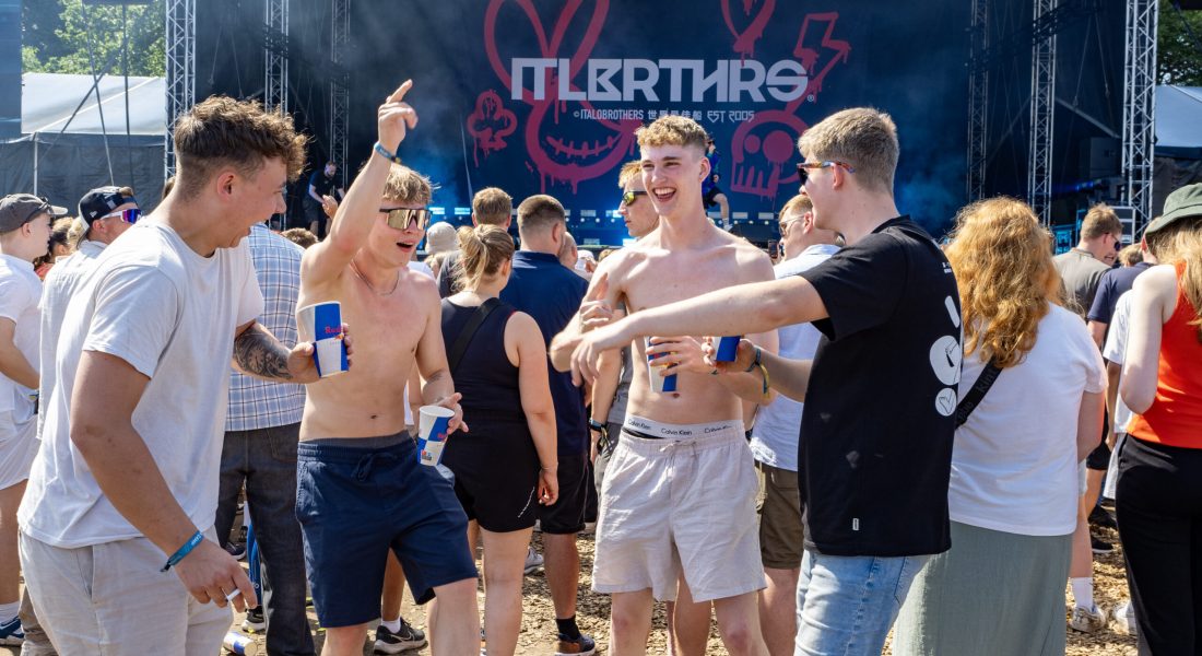 Unge mænd fester foran scenen til ItaloBrothers på Skive Festival med kolde drinks i hænderne på Strandtangen.
