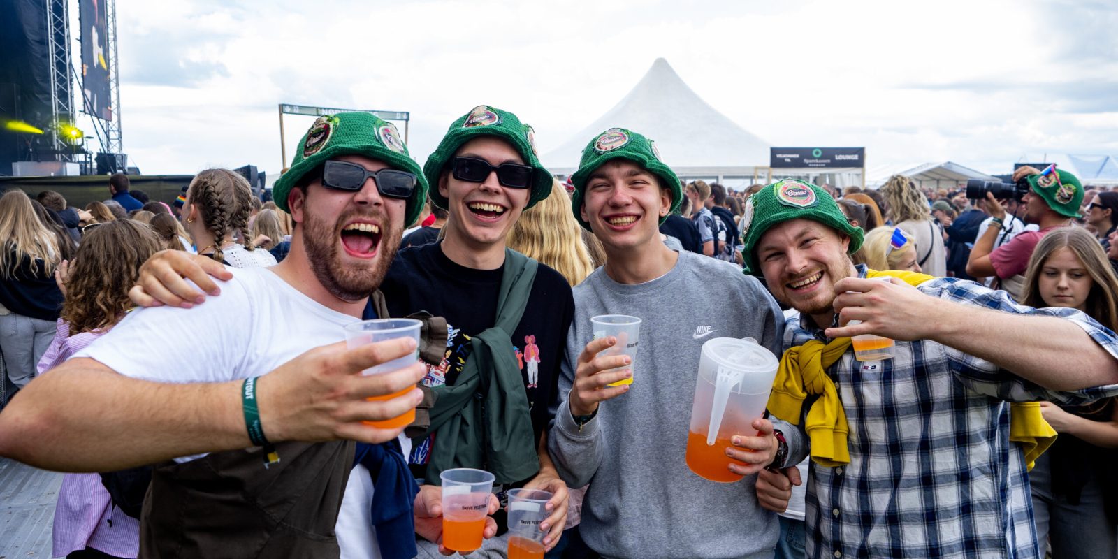 Fire venner med grønne bøllehatte og drinks nyder festivalstemningen på Skive Festival.