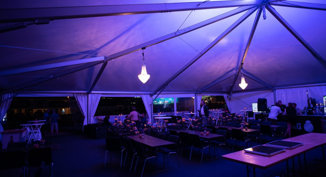 Interiør fra Sparekassen Danmark Lounge på Skive Festival med lilla lys, lysekroner og dækkede borde.