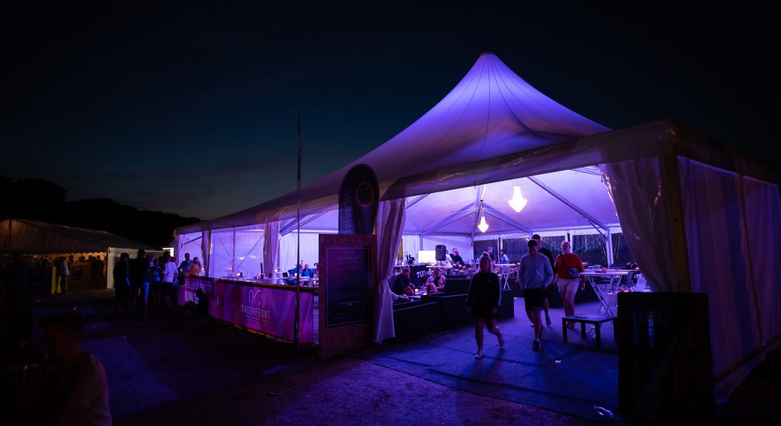 Oplyst VIP-telt med lilla lys om natten i Sparekassen Danmark Lounge på Skive Festival på Strandtangen.