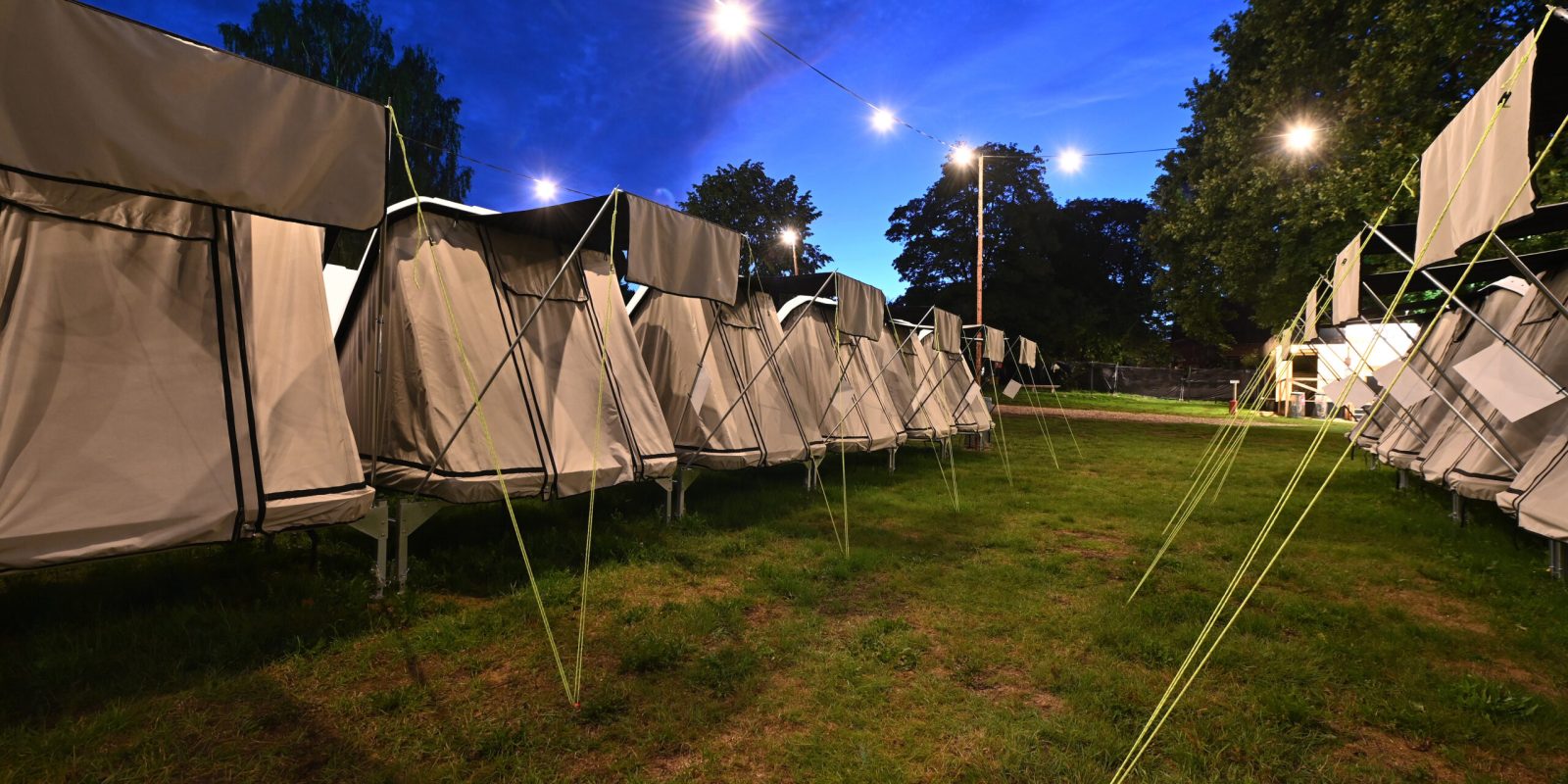 Rækker af opstillede telte på Lux Camp til Skive Festival under en blå aftenhimmel med lyskæder.