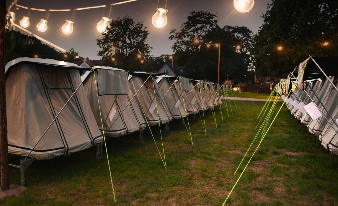 Lux Camp festivalovernatning på Skive Festival Rækker af hvide telte i Lux Camp på Skive Festival oplyst af hyggelige lyskæder om aftenen på græsset.
